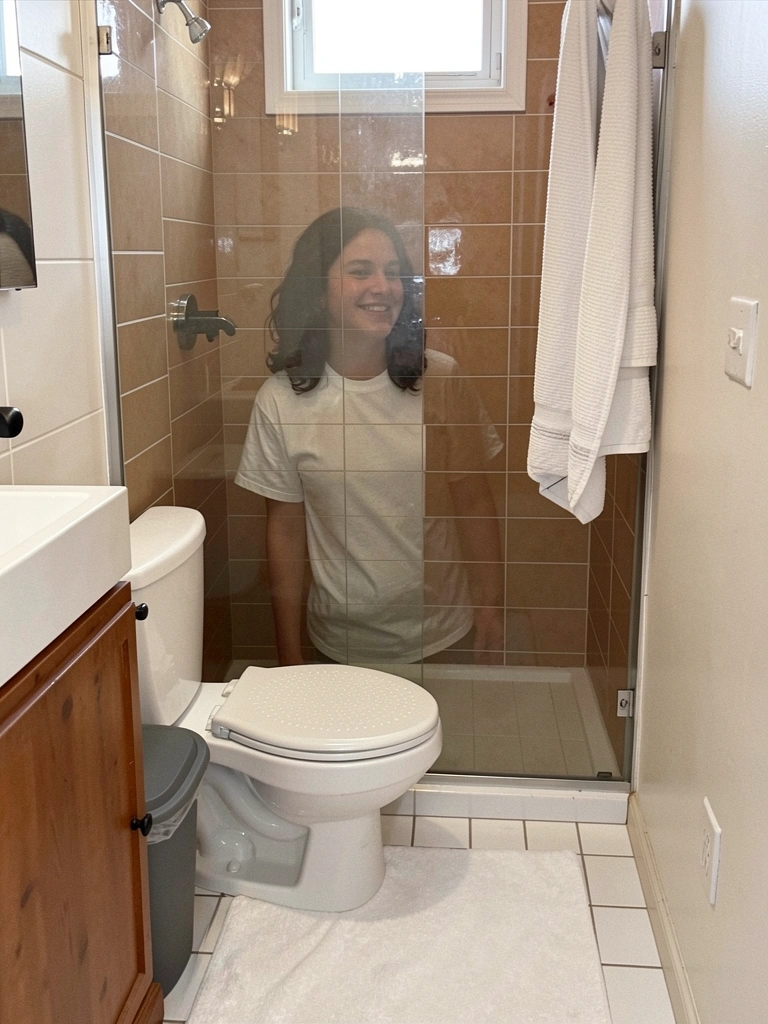 Torneira monocomando preta fosca ao lado de vaso sanitário com caixa acoplada, parede clara.