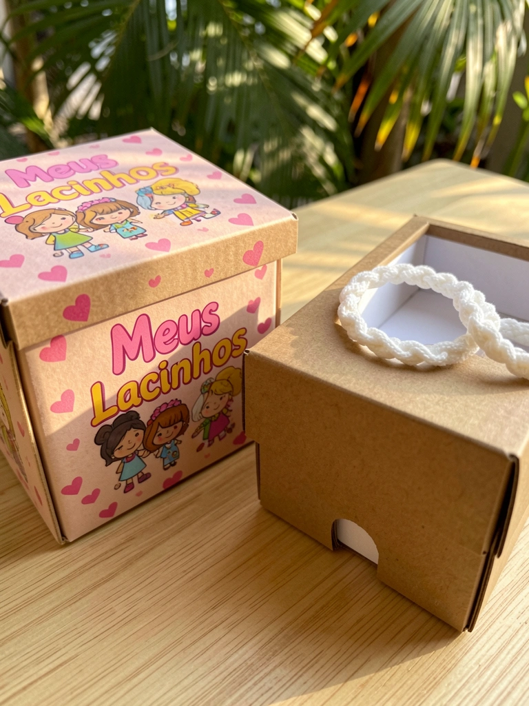 Caixas de papelão sobre madeira clara: uma com estampa colorida de personagens e "Meus Lacinhos", outra lisa com lacinhos trançados brancos na borda, luz natural com sombras suaves.