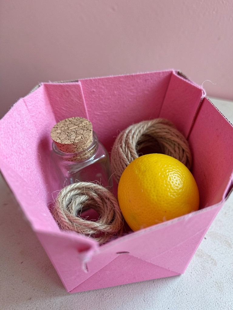 Potes de vidro, garrafas e barbante sobre uma mesa, com frutas ao lado, compondo um arranjo de materiais recicláveis.