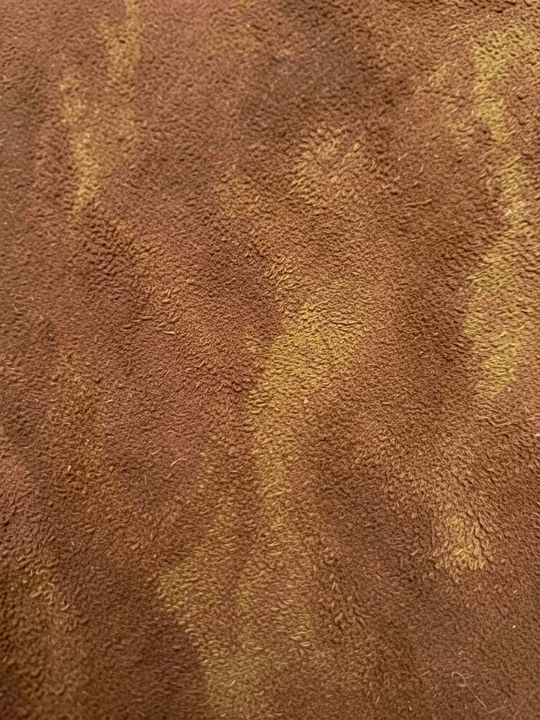 Close-up de superfície texturizada marrom, semelhante a couro, com variações sutis de tom e grão, iluminação natural difusa.