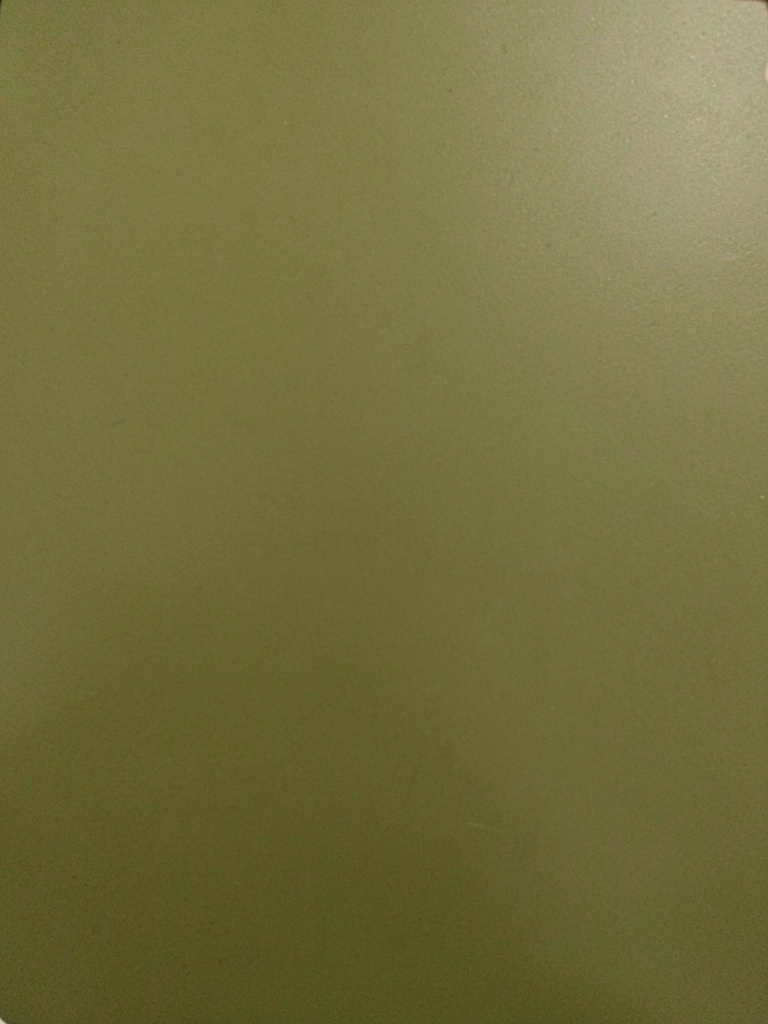Sala de estar com sofá verde musgo, paredes claras e mesa de centro de madeira, luz natural entrando pela janela.