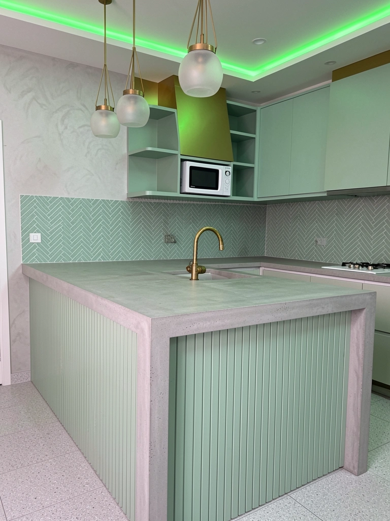 Cozinha com azulejo verde-menta, bancada branca e eletrodomésticos embutidos.