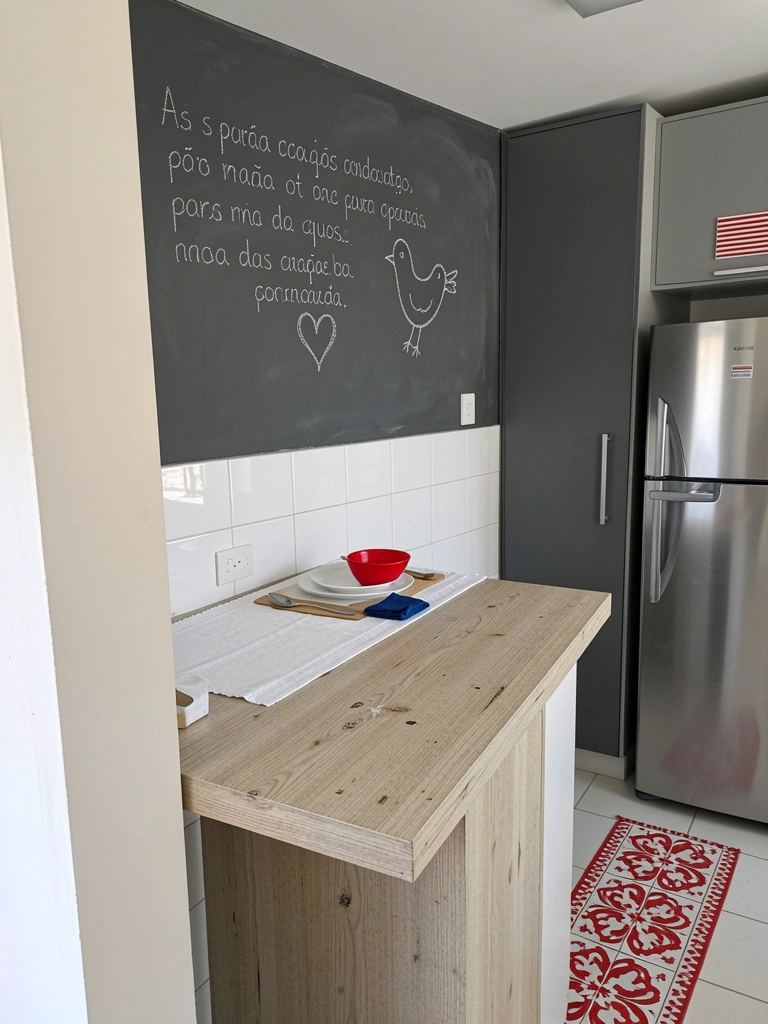 Bancada de cozinha compacta em madeira clara com armários brancos e eletrodomésticos embutidos