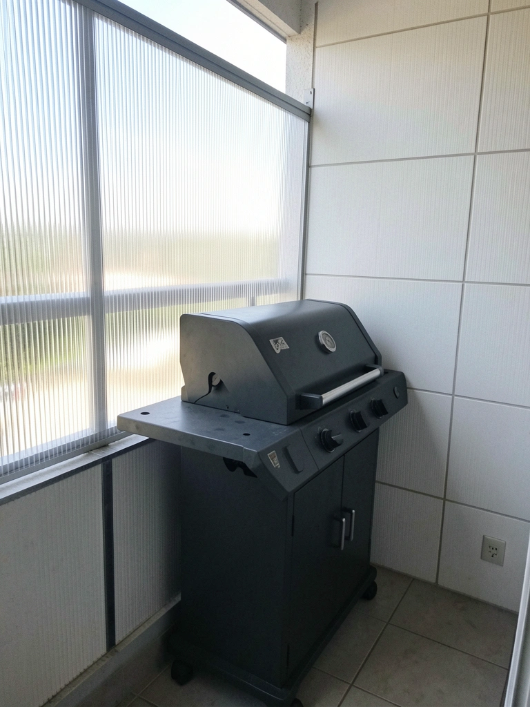 Varanda com churrasqueira e painel de PVC vazado separando ambientes.