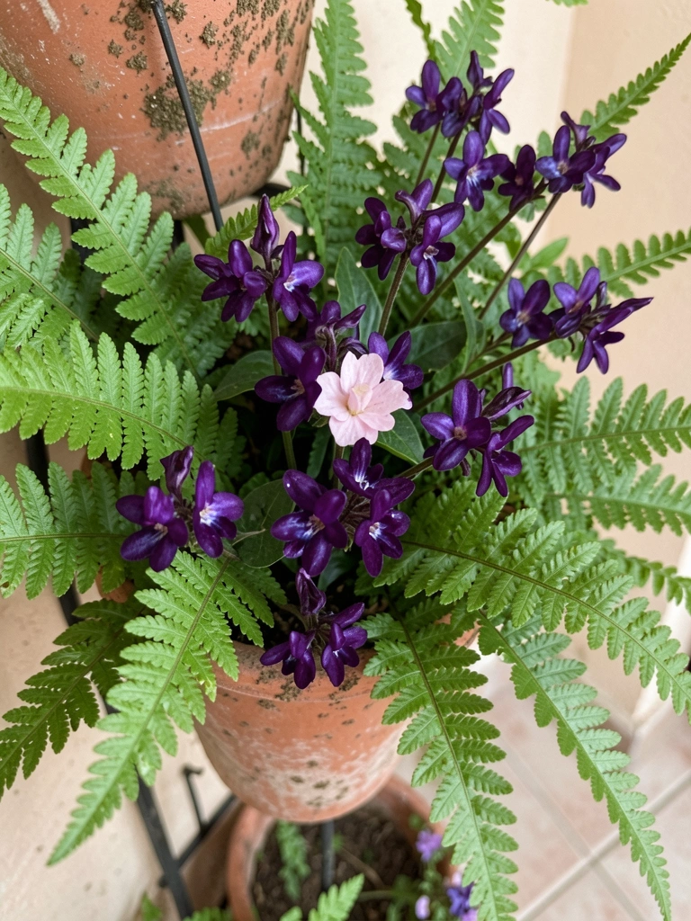 Jardim vertical com samambaias verdes e flores roxas em vasos modulares.