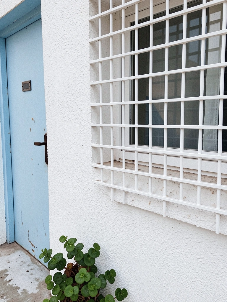Grade de alumínio branca instalada em janela com vista para o mar.