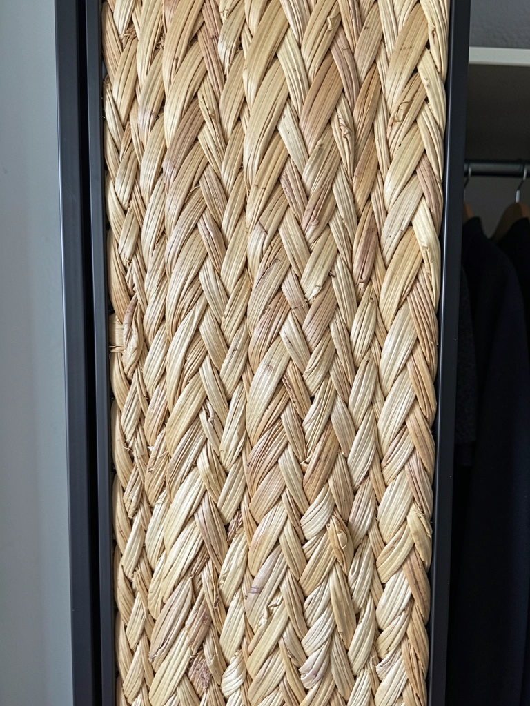 Detalhe de porta de guarda-roupa com palha natural de algodão trançada, textura artesanal.