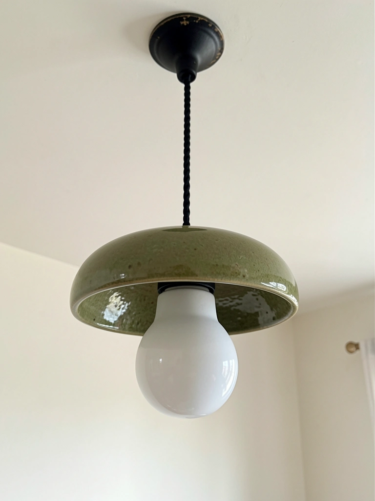 Lustre de cristal pendurado no teto de um quarto com acabamentos claros e iluminação suave.