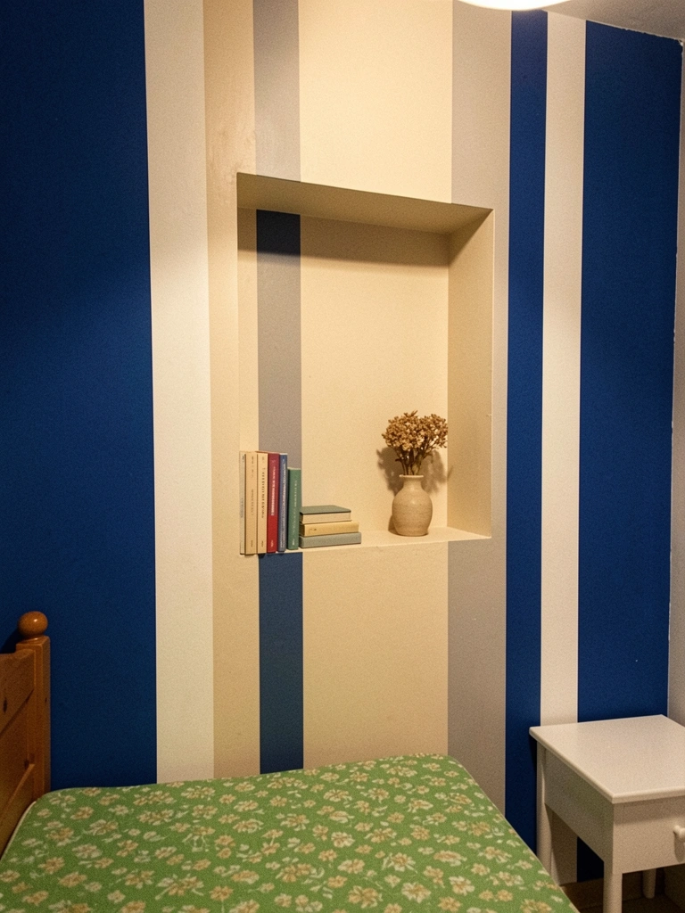 Nicho retangular em parede clara ao lado de cama, com livros empilhados e um vaso pequeno.