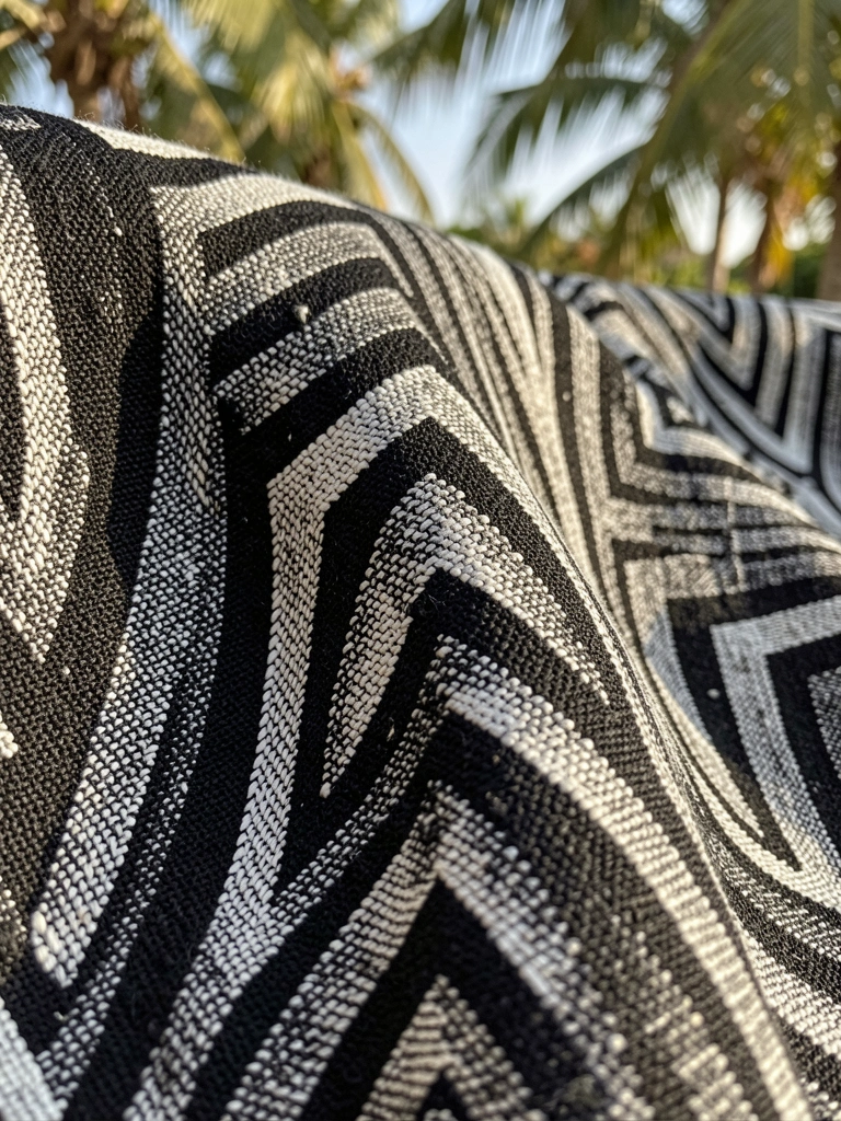 Tecido de linho preto com padrão xadrez geométrico em branco e cinza, textura elevada e luz natural suave.