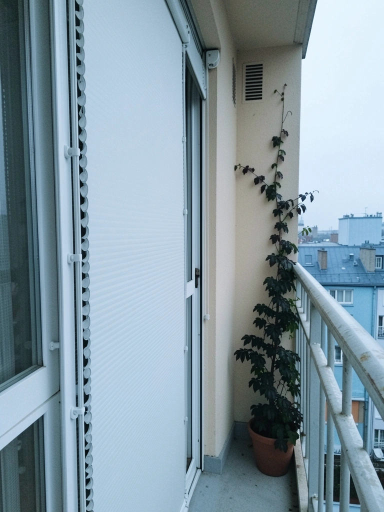Persiana vertical instalada em varanda com porta de vidro deslizante ao fundo.
