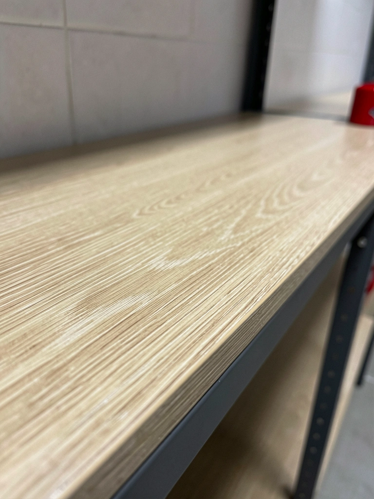 Detalhe da superfície de uma prateleira metálica com revestimento anticorrosivo texturizado, iluminação lateral destacando a granulação.