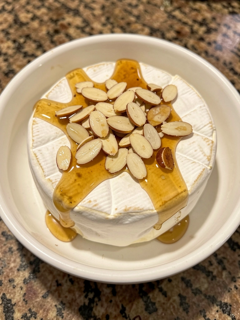 Flautas de champanhe ao lado de fatias de brie e uvas verdes em uma tábua de madeira.