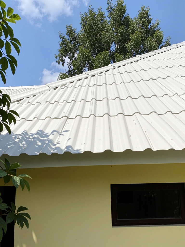 Casa com telhado de PVC branco e árvore ao fundo, vista externa.