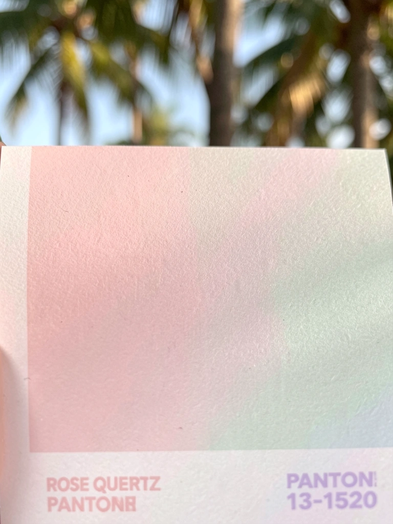 Amostra de Rose Quartz Pantone 13-1520 em close, com textura suave e tons de lilás e verde menta, iluminada por luz natural difusa.