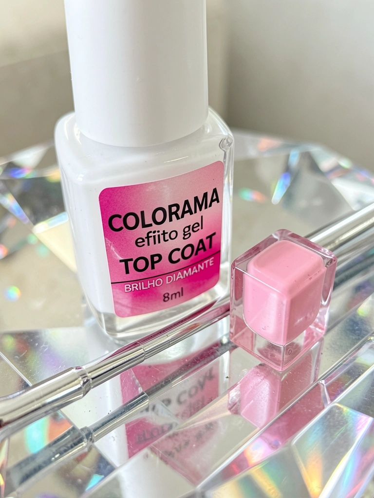 Frasco branco de esmalte Top Coat e pincel prateado sobre superfície de cristal refletiva, com luz difusa criando brilhos.