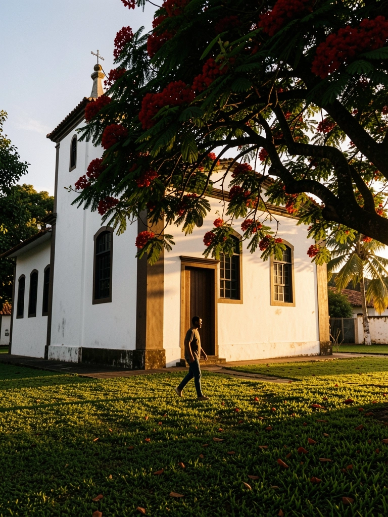 Igreja branca com janelas escuras e porta de madeira sob árvore florida, luz dourada do pôr do sol e sombras na grama; homem caminha no primeiro plano.