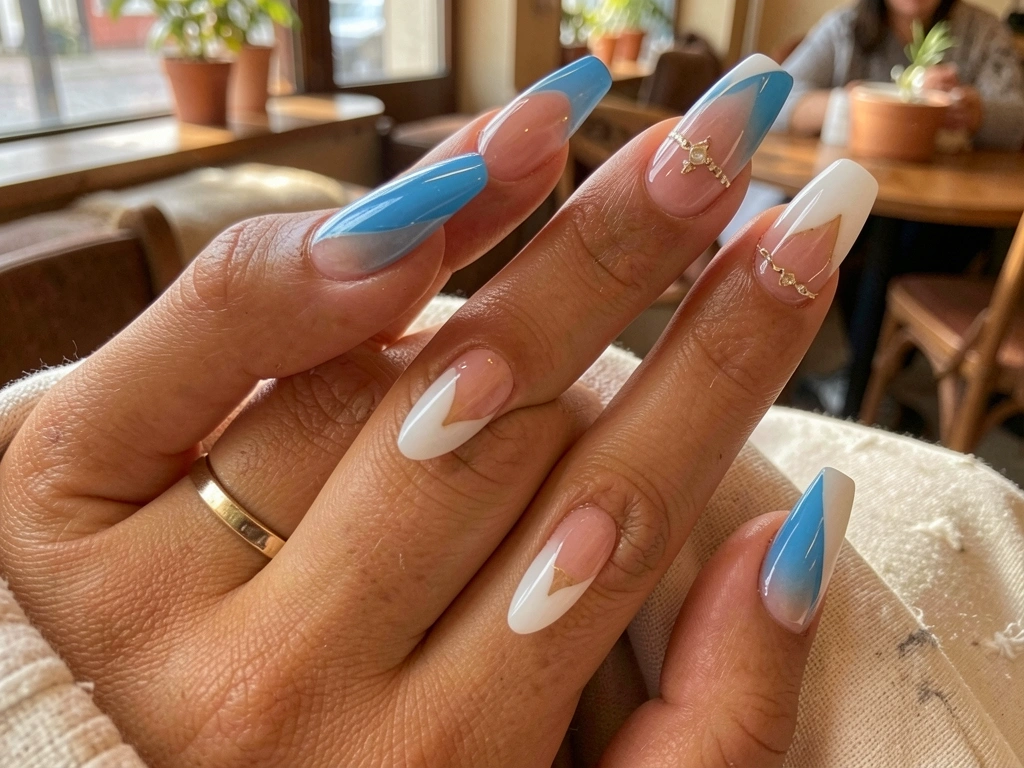 Mãos com unhas decoradas em gradiente azul e branco com detalhes sutis, descansando sobre tecido texturizado em ambiente iluminado por luz natural.