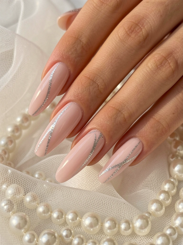 Unhas longas e finas com esmalte rosa claro e glitter prateado fino, fundo desfocado de tule branco e pérolas, luz natural difusa destacando o brilho.