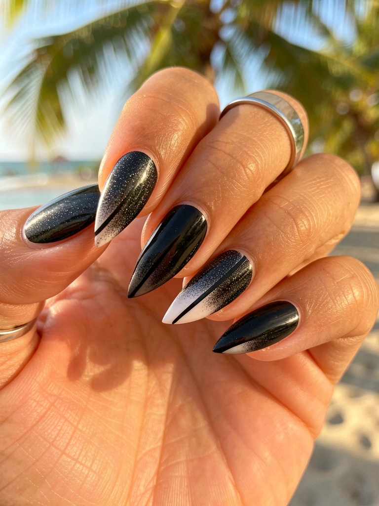 Mão com unhas em gel preto e glitter, formato angular, anel prateado no dedo anelar, luz natural quente.