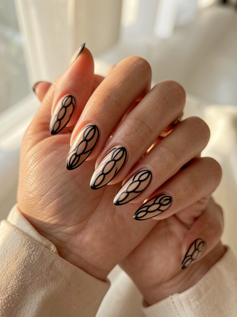 Mãos entrelaçadas com unhas ovais alongadas em nude e preto, detalhes em contorno escuro, luz natural suave e fundo desfocado.