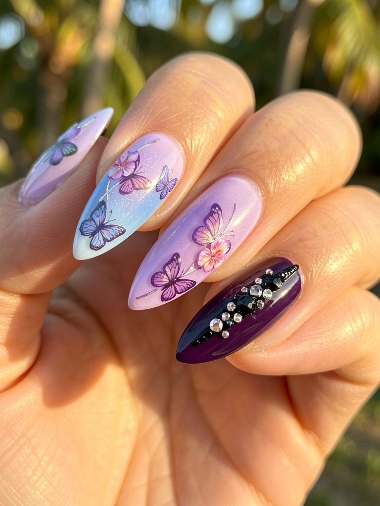 Macro de unhas em gel: uma com degradê lavanda e azul, borboleta e flores em roxo e rosa; outra roxa escura com detalhe preto e cristal. Fundo desfocado com luz natural.
