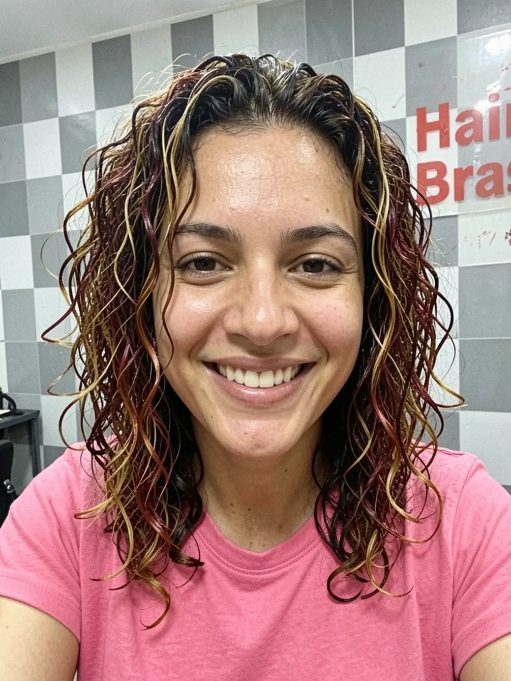 Cabelo cacheado médio com camadas, mechas castanho-escuras e douradas, raiz avermelhada, brilho úmido e textura definida.