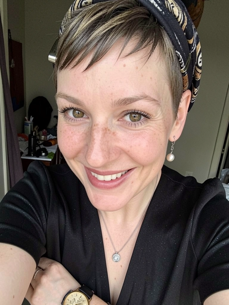 Cabelo pixie curto com presilha metálica lateral e lenço amarrado na cabeça.
