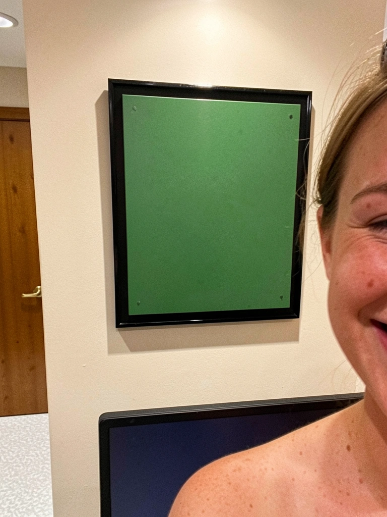 Placa quadrada verde com moldura preta fixada acima de um monitor.