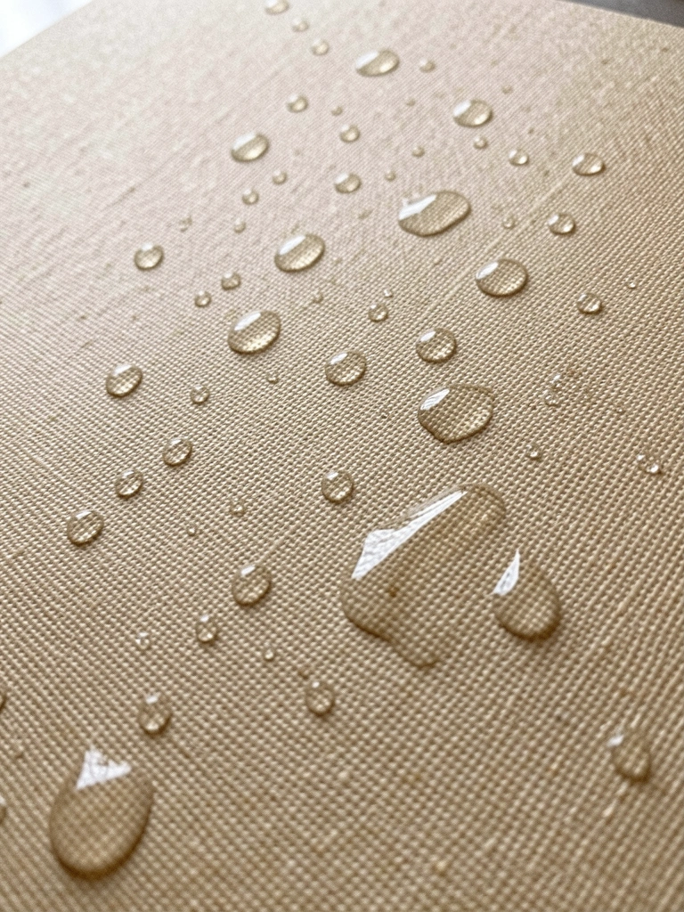 Close de papel linho natural com textura vinílica e gotas de água.
