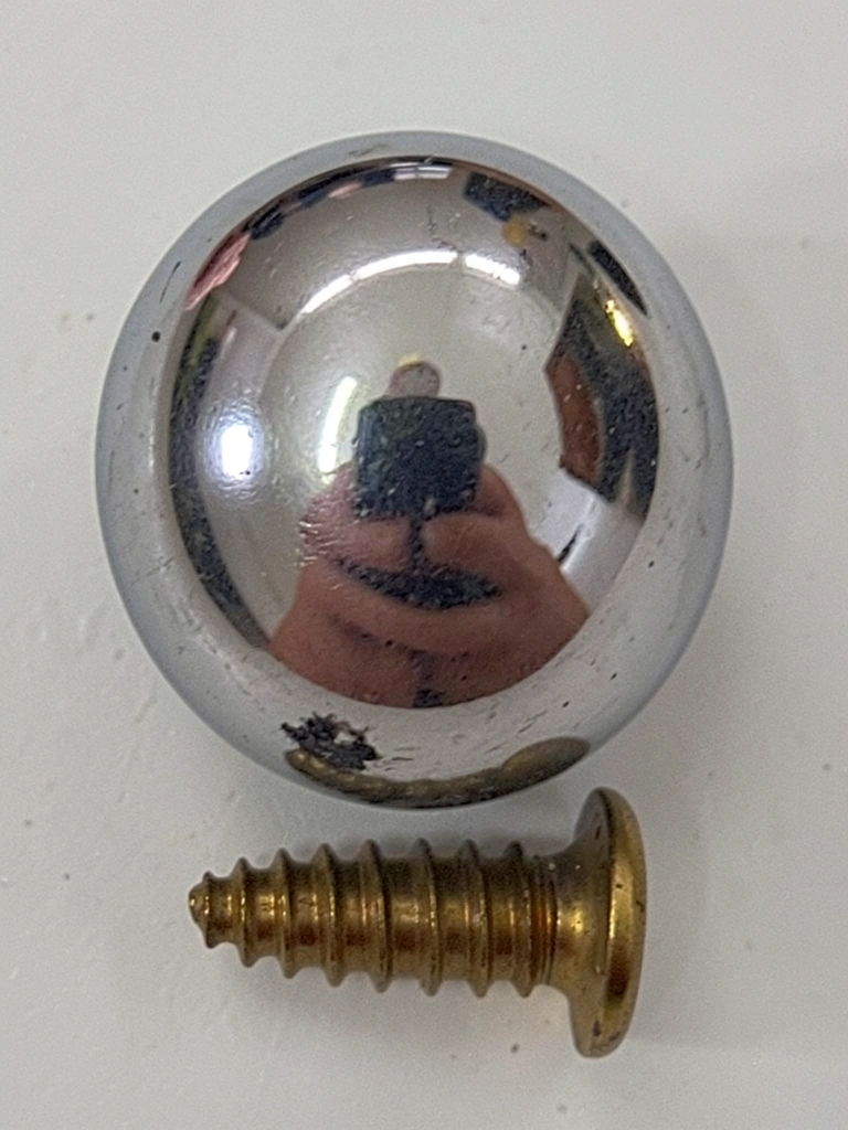 Puxador de vidro redondo transparente com base cromada brilhante em armário de cozinha moderno.