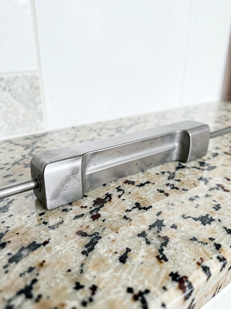Puxador de aço inox longo em cozinha planejada com bancada de granito.
