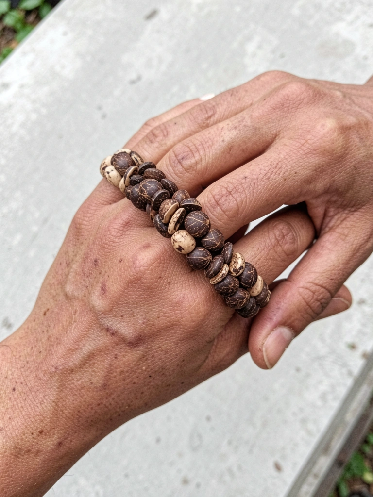 Duas mãos entrelaçadas com anéis de tucum e uma aliança, fundo de natureza.
